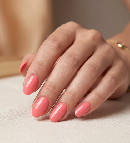 Hand with pink nail polish on a neutral background