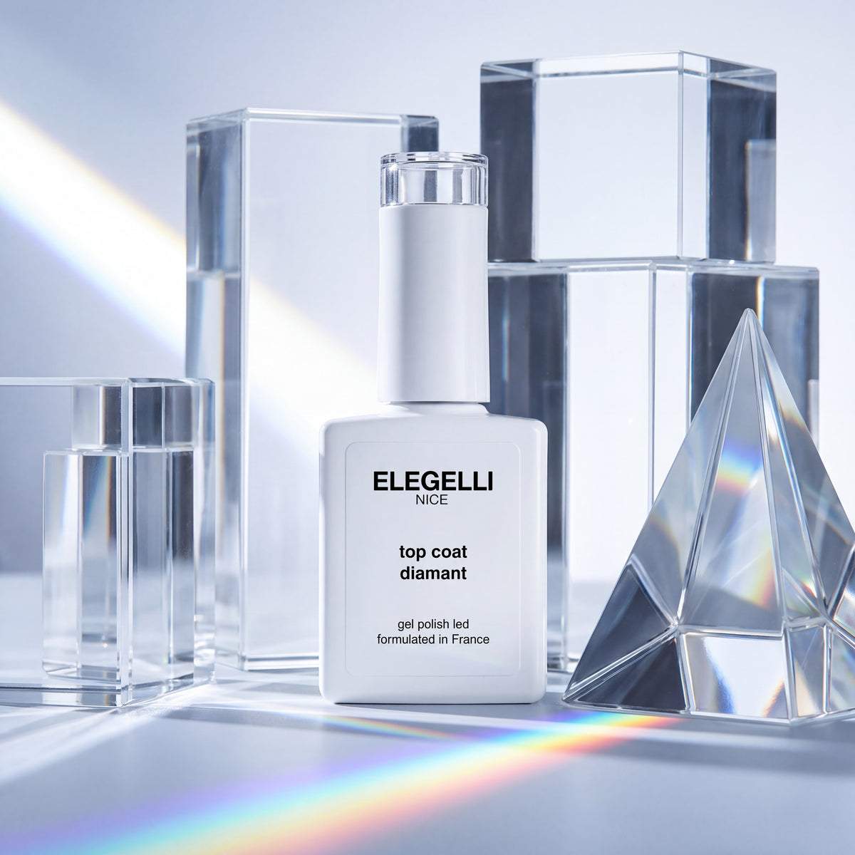 Флакон Elegelli Diamond Top Coat среди прозрачных стеклянных блоков рядом с призмой, отбрасывающей радугу
